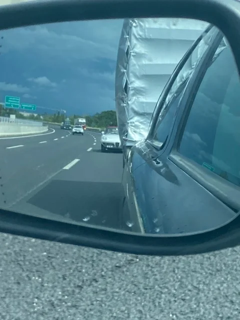 Zijspiegel met de aanhanger en de Alfa Romeo Duetto op de Italiaanse snelweg